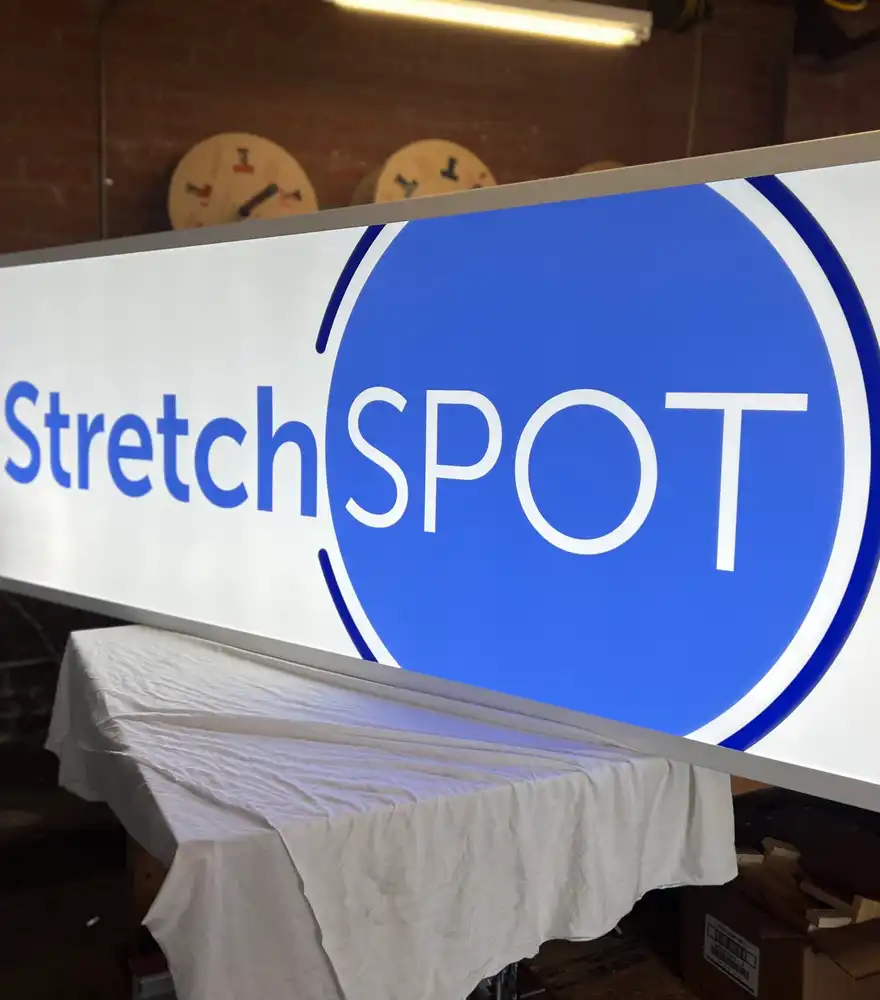 Illuminated lightbox sign panel in production inside the DVS Signage fabrication shop