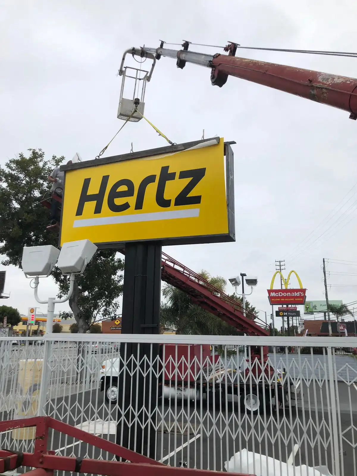 Crane installing a Hertz pole sign
