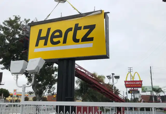 Crane installing a Hertz pole sign