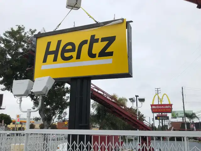 Crane installing a Hertz pole sign
