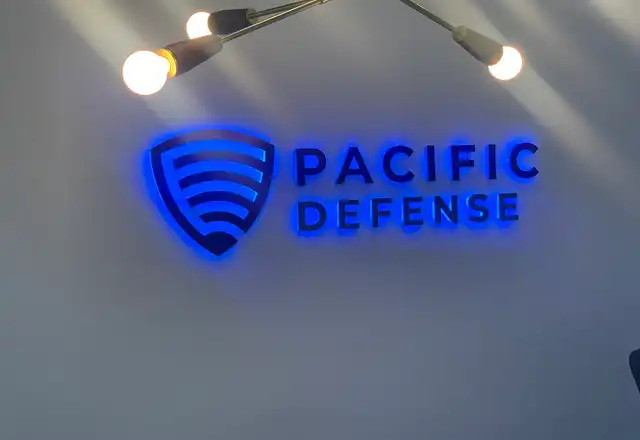 Halo-lit Pacific Defense logo and lettering on a lobby wall