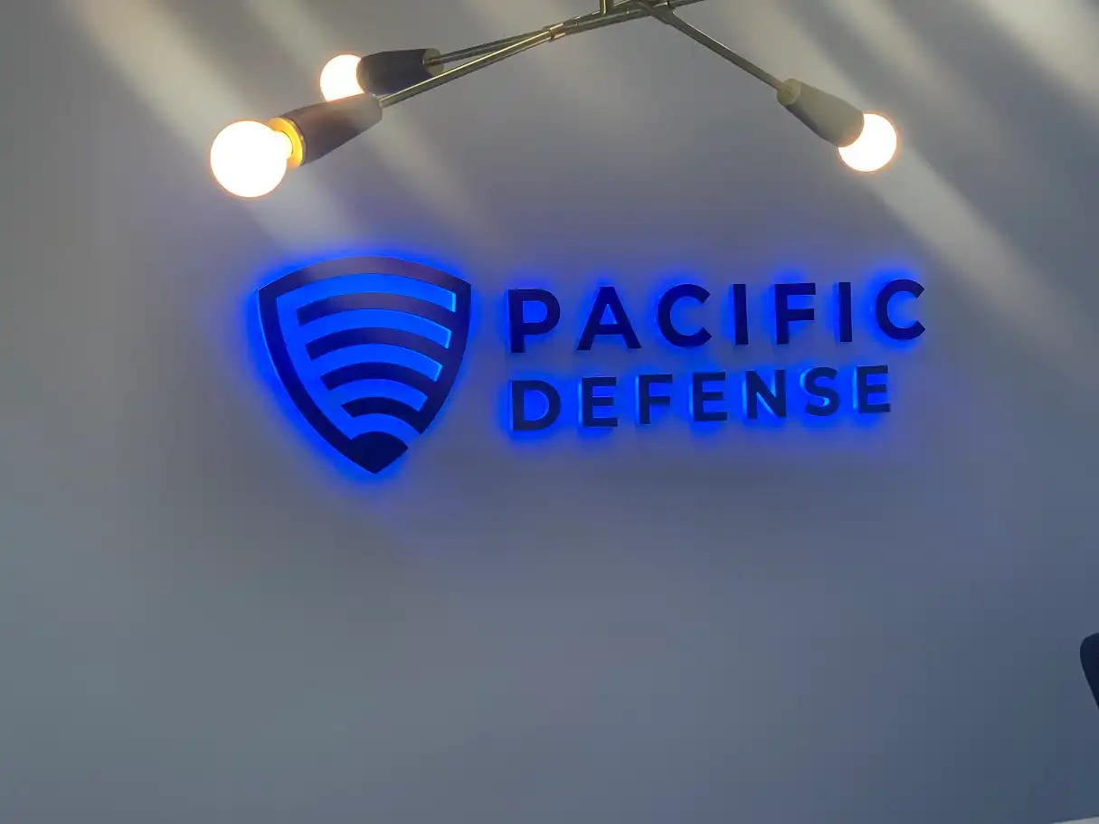 Halo-lit Pacific Defense logo and lettering on a lobby wall
