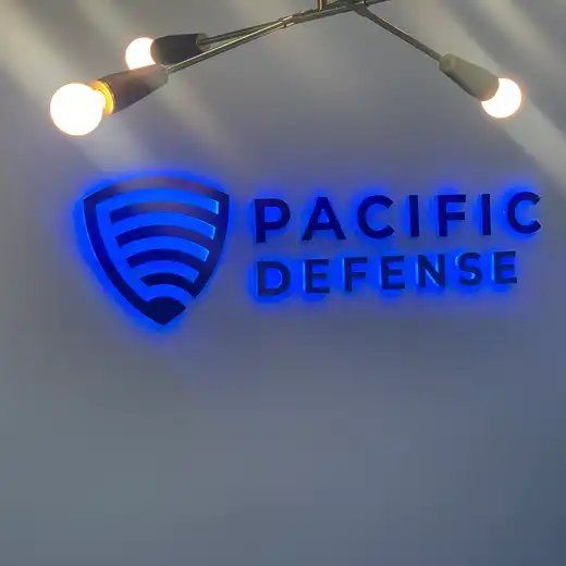 Halo-lit Pacific Defense logo and lettering on a lobby wall