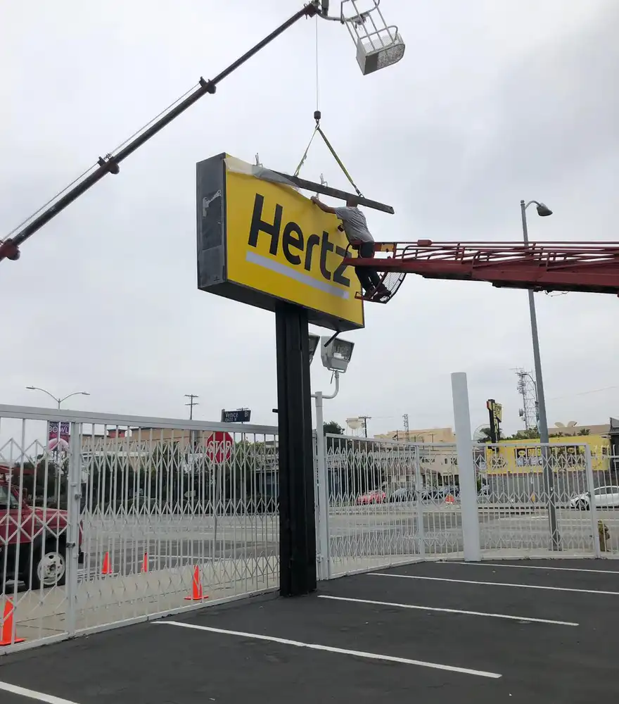 Crane installing a large pole sign at a commercial property