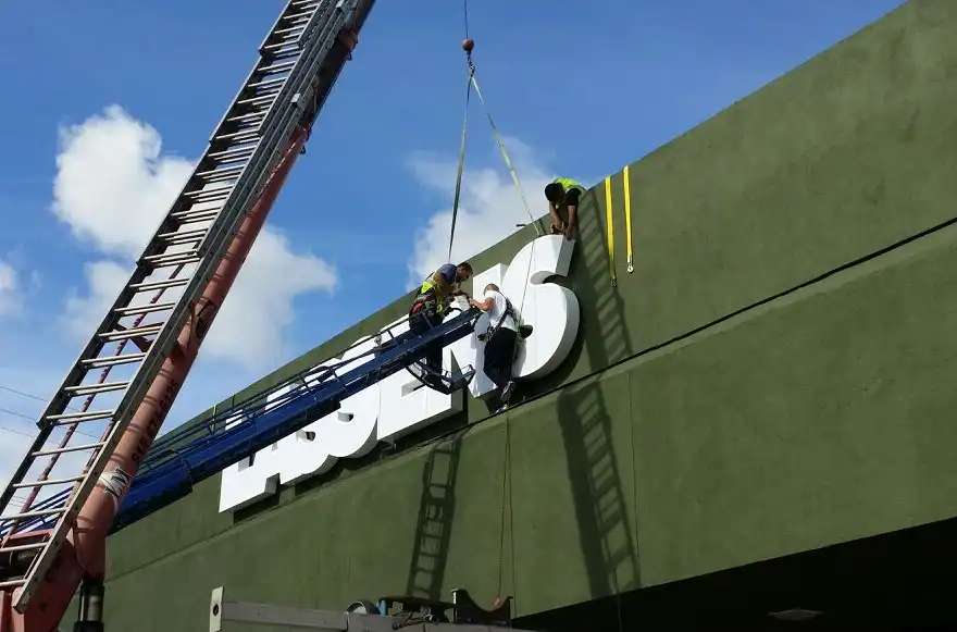 Installation crew mounting large channel letters on a commercial building facade