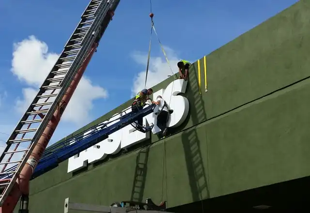 Installation crew mounting large channel letters on a commercial building facade